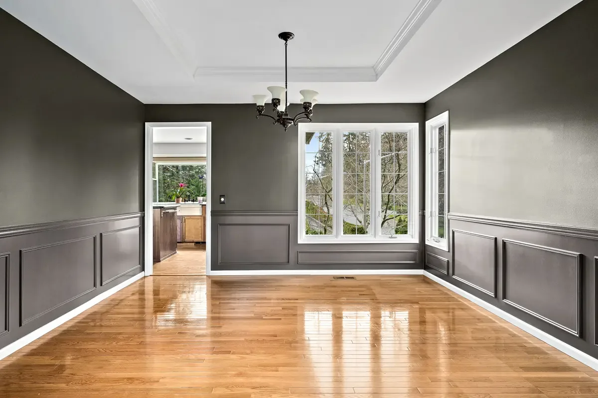 Formal dining room with dark gray walls, white wainscoting and crown molding, freshly painted